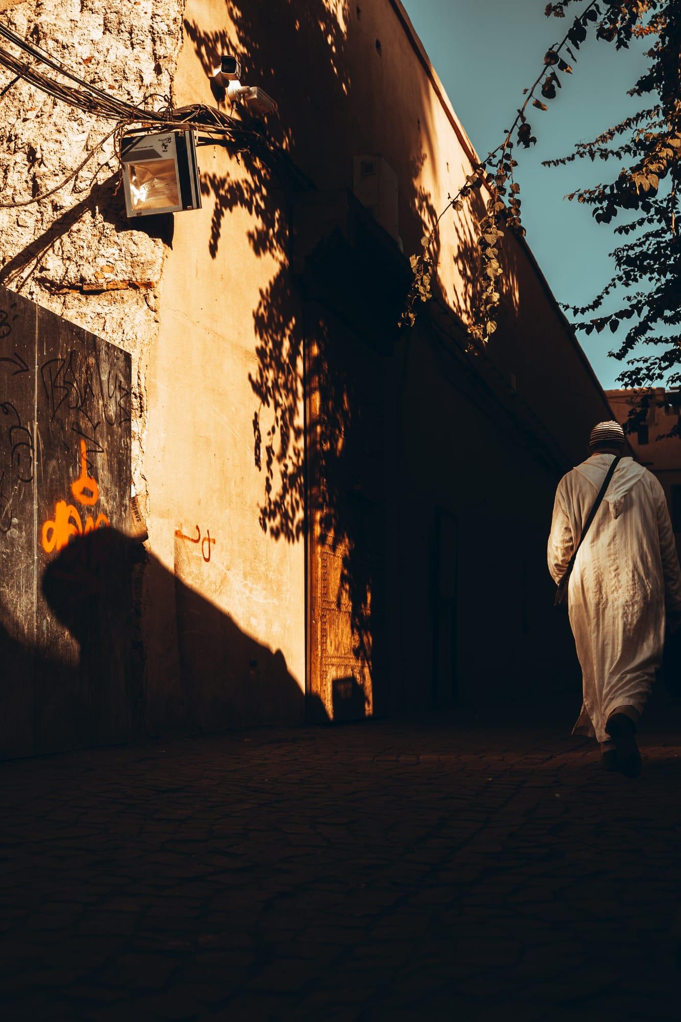 Une silhouette remonte une ruelle au soleil de fin de journée