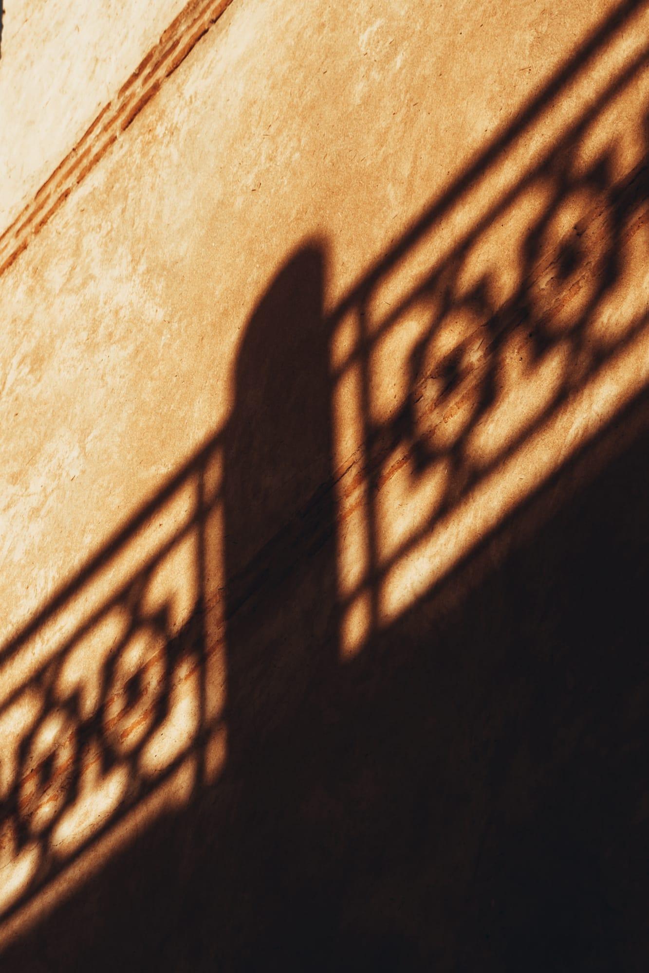 L’ombre d’une grille en fer forgé sur un mur de plâtre