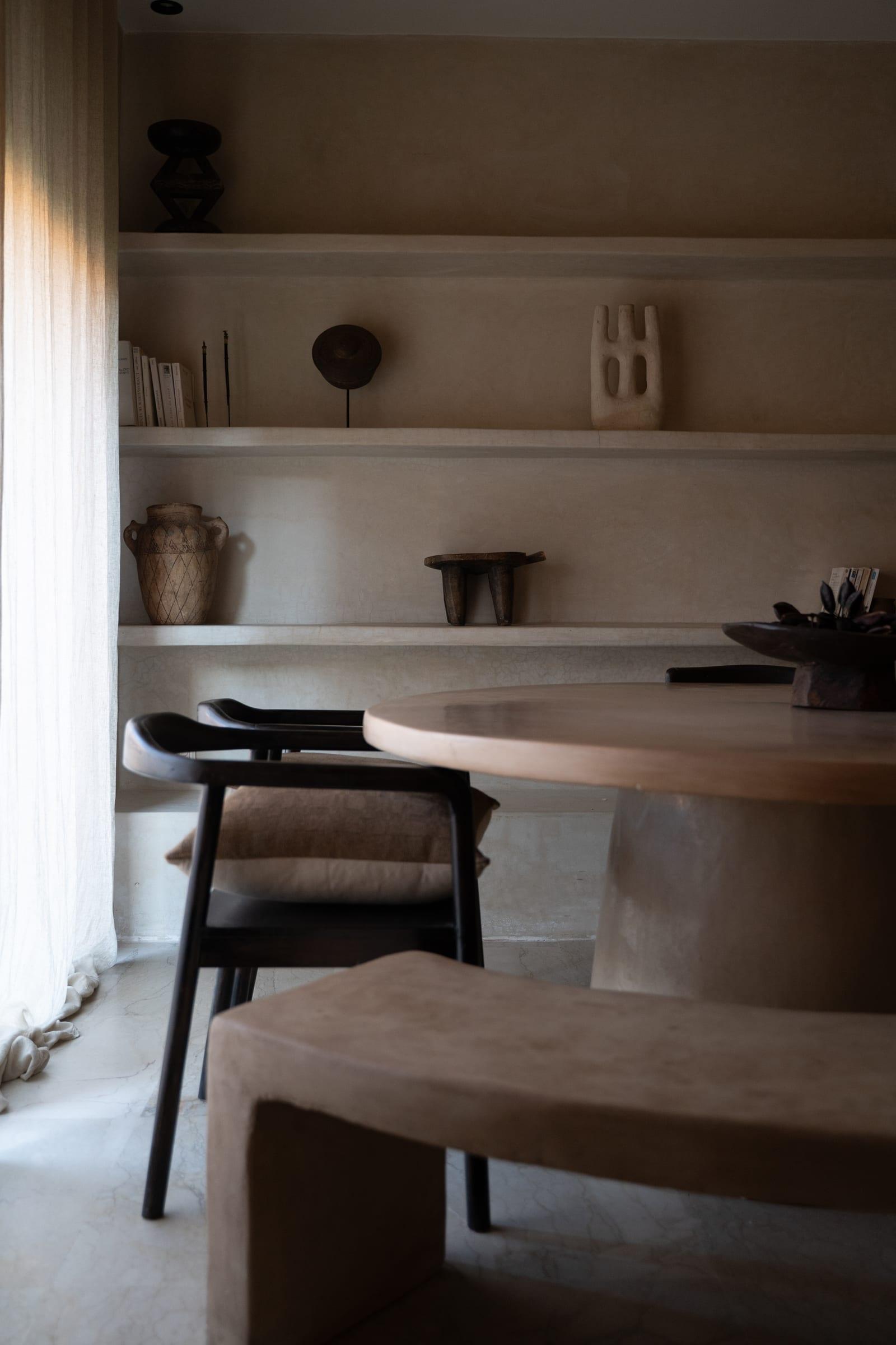 Un séjour : table ronde, chaise noire, étagères de plâtre